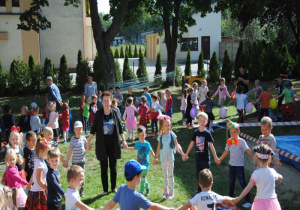 szystkie dzieci tańczą w grupowych kołach, trzymając balony i śpiewają piosenkę